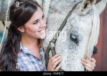 Lächelnde Frau Pflege für ein Pferd auf einem Bauernhof Stockfoto