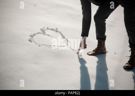 Mann malen Herzen im Schnee Stockfoto