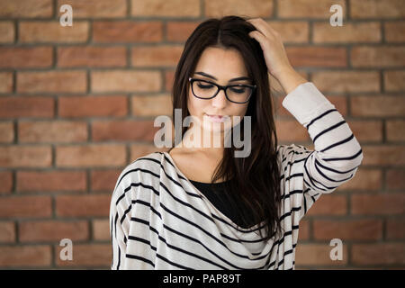 Porträt der jungen Frau mit langen braunen Haaren mit Brille Stockfoto