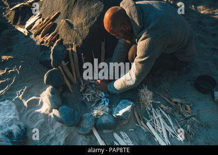 Norwegen, Lofoten, Moskenesoy, junge Männer Vorbereitung Lagerfeuer am Strand von kvalvika Stockfoto