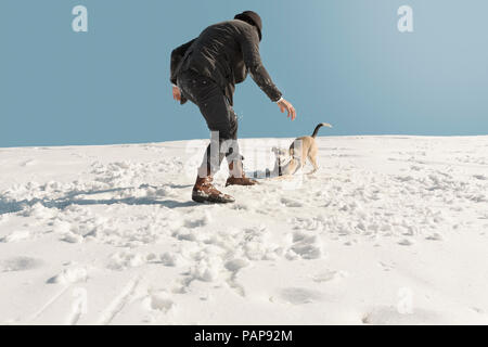 Mann spielt mit Hund im Winter, Spaß im Schnee Stockfoto