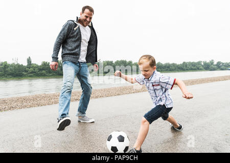 Gerne Vater und Sohn auf Fußball spielen, am Flußufer Stockfoto