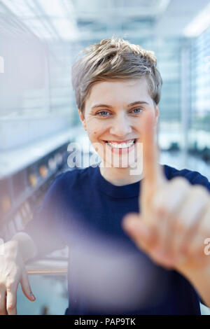 Portrait von blond Geschäftsfrau zu berühren Glasscheibe Stockfoto