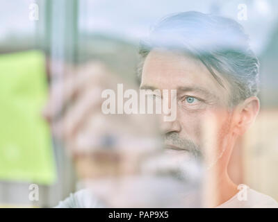Geschäftsmann auf kurznotiz an der Glasscheibe Stockfoto