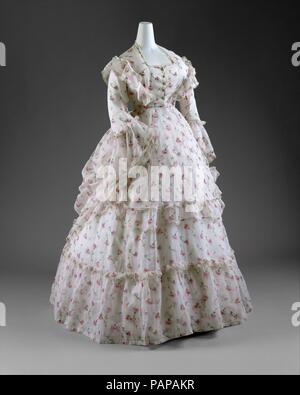 Kleid. Kultur: Französisch. Datum: Ca. 1872. Die 1870er Jahre war die Zeit der Romantik und Spleen im schicken Kleid. Ähnlich wie die malerische Gemälde von Renoir, dass solche Süßwaren Kreationen zeigen, sowohl am Tag als auch am Abend Kleider waren sehr verziert und oft in zarten, femininen Textilien ausgeführt. Obwohl abendmode von Dekolleté Dekolletés und verschwenderischen Seide Satins und taffetas gekennzeichnet war, tag Kleider waren mehr bescheiden mit strengen Stoffen wie Baumwolle oder Wolle. Während viele Frauen im Besitz wandern und reisen Kleider, die etwas größere moveability geleistet, auch durchaus üblich war die Stockfoto