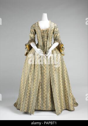 Robe à la Française. Kultur: Französisch. Datum: 1760-70. Frauen mit kokett Airs waren beeindruckend in Robe à la Française und Robe à l'Anglaise über den gesamten Zeitraum zwischen 1720 und 1780. Die robe à la française aus dem losen Negligé sacque Kleid der früheren Teil des Jahrhunderts, die Falten von den Schultern an der Front war auf der Rückseite abgeleitet wurde. Die Silhouette, die aus einem Trichterförmigen büste Einspeisung in große rechteckige Röcke, wurde von spanischen Designs des vorigen Jahrhunderts inspiriert und erlaubt für große Mengen von Textilien mit zarten Rokoko kurvenförmige Dekoration. Die Stockfoto