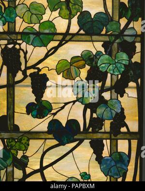 Grapevine Panel. Kultur: American. Designer: Das von Louis Comfort Tiffany (American, New York 1848-1933 New York). Abmessungen: 98 x 36 in. (248.9 x 91,4 cm). Teekocher: Tiffany Studios (1902-32). Datum: Ca. 1902-15. Diese sehr dekorative Platten (siehe auch 1978.19.1) verfügen über üppige Trauben und Reben auf eine geradlinige Trellis miteinander verbunden. Die breiten Blätter sind in einer Vielzahl von grünen berührte mit blauen, violetten gerendert, und sogar Rosa. Die Schlanken - - Reben - Einige führen, einige Glas-- drehen sich rund um das Gitter, während die abgerundeten, dreidimensionale Formen der Trauben die Illusion weiter zu verbessern Stockfoto