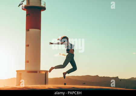 Junge Frau in der Wüste Landschaft am Leuchtturm springen Stockfoto