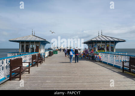 Touristen entlang der schönen alten Pier spazieren in Llandudno im Norden von Wales. Stockfoto