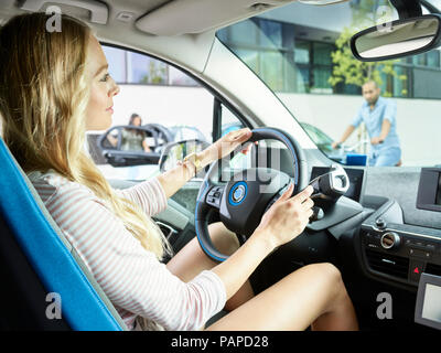 Lächelnde Frau fahren Elektroauto Stockfoto