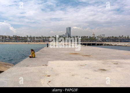 Leute sitzen und laufen auf Barceloneta Wellenbrecher. Blick auf den Strand von Barceloneta aus Gas Wellenbrecher. Stockfoto