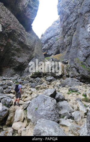 Eine touristische klettert auf den Felsen an der Basis der Gordale Scar, die vollständig in die derzeitige Hitzewelle im Juli 2018 getrocknet ist Stockfoto