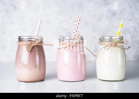Satz von milchshake in Töpfen. Banane Schoko und Erdbeere Milchshakes mit Muttern und Kokosnuss. Sommer Nachtisch. Gesundes Essen. Stockfoto