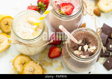 Satz von milchshake in Töpfen. Banane Schoko und Erdbeere Milchshakes mit Muttern und Kokosnuss. Gesundes Essen. Stockfoto