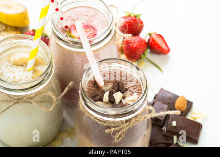 Satz von milchshake in Töpfen. Banane Schoko und Erdbeere Milchshakes mit Muttern und Kokosnuss. Nahaufnahme Stockfoto