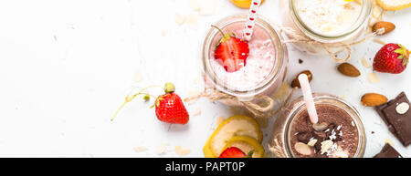 Satz von milchshake in Töpfen. Banane, Schokolade und Erdbeeren Milchshakes mit Muttern und Kokosnuss. Lange banner Format. Stockfoto