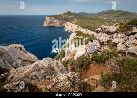 Frau wandern im Querformat von Grotta dei Vasi Rotti gesehen neben Capo Caccia auf der italienischen Insel Sardinien Stockfoto