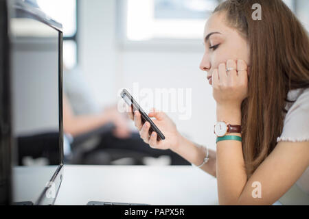 Junges Mädchen mit Handy in Computer klasse Stockfoto