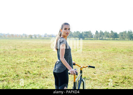 Sportliche junge Frau mit dem Fahrrad auf einer Wiese Stockfoto