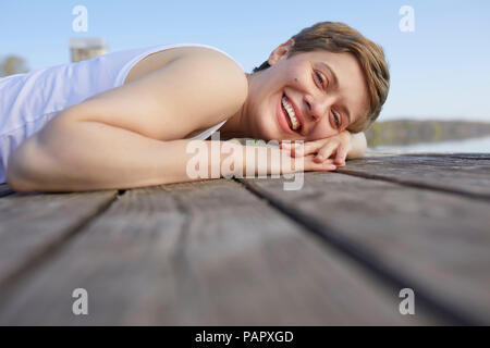 Portrait von Lachen liegende Frau auf Jetty Stockfoto