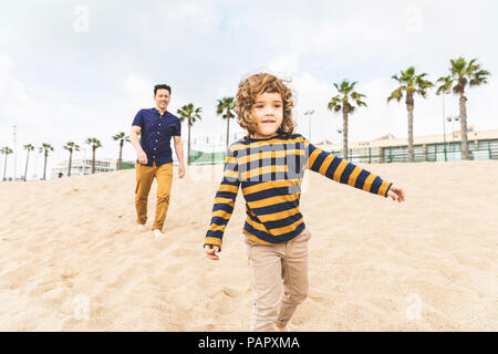 Spanien, Barcelona, Vater und Sohn zu Fuß am Strand Stockfoto