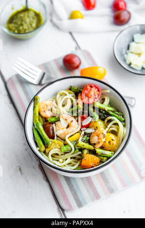 Spaghetti mit Garnelen, grüner Spargel, Tomaten, Pesto und Parmesan Stockfoto