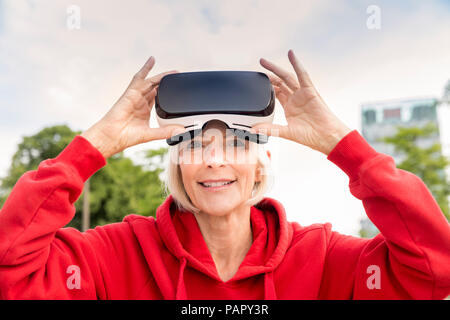 Portrait von lächelnden älteren Frau mit VR-Brille Stockfoto