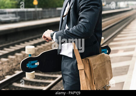 Nahaufnahme der Geschäftsmann mit Skateboard am Bahnsteig warten Stockfoto