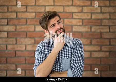 Portrait von nachdenklicher junger Mann vor der Mauer Stockfoto