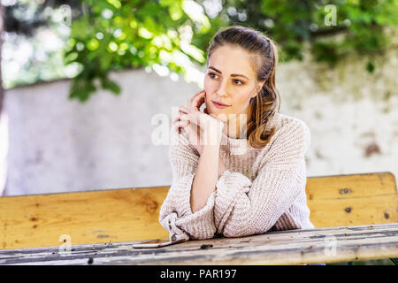 Portrait von nachdenklich Frau sitzt auf der Bank im Courtyard Stockfoto