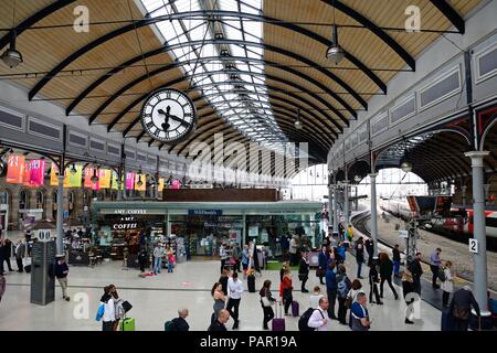 Passagiere warten am Bahnsteig in der Newcastle Hauptbahnhof mit Geschäften und Cafés an der Rückseite, Newcastle upon Tyne, Tyne und Wir Stockfoto