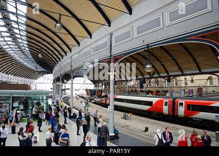 Passagiere warten am Bahnsteig in der Newcastle Hauptbahnhof mit Geschäften und Cafés an der Rückseite, Newcastle upon Tyne, Tyne und Wir Stockfoto