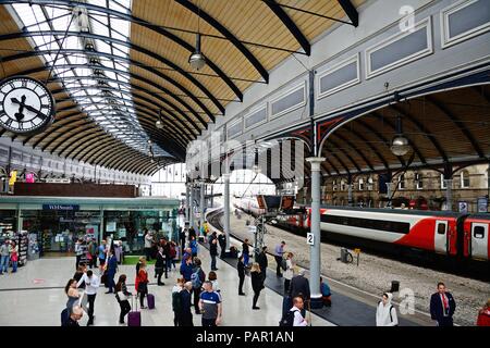 Passagiere warten am Bahnsteig in der Newcastle Hauptbahnhof mit Geschäften und Cafés an der Rückseite, Newcastle upon Tyne, Tyne und Wir Stockfoto