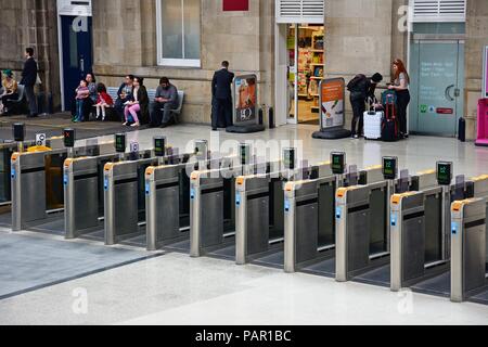 Reihe von Ticket Barrieren innerhalb Newcastle Hauptbahnhof mit Passagiere warten auf der Rückseite, Newcastle upon Tyne, Tyne und Wear, England, Vereinigtes Königreich, Stockfoto