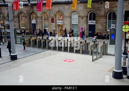 Reihe von Ticket Barrieren innerhalb Newcastle Hauptbahnhof mit Passagiere warten auf der Rückseite, Newcastle upon Tyne, Tyne und Wear, England, Vereinigtes Königreich, Stockfoto