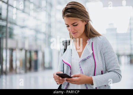 Junge Frau mit Handy am Flughafen Stockfoto