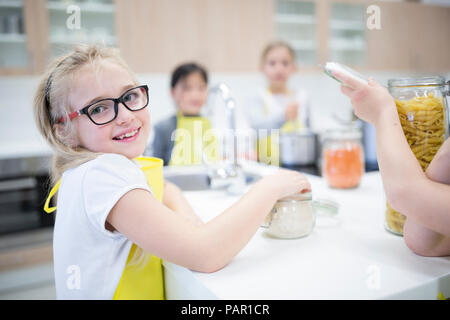 Portrait von lächelnden Schulmädchen mit classmtes im Kochkurs Stockfoto