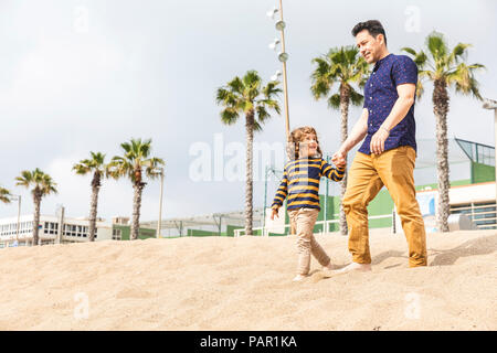 Spanien, Barcelona, Vater und Sohn gehen Hand in Hand am Strand Stockfoto