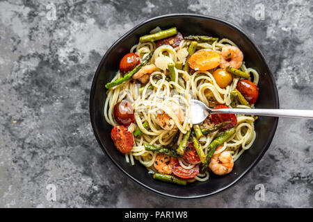 Spaghetti mit Garnelen, grüner Spargel, Tomaten, Pesto und Parmesan Stockfoto