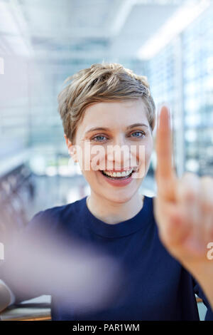 Portrait von blond Geschäftsfrau zu berühren Glasscheibe Stockfoto