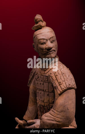 Porträt eines isolierten Terracotta Krieger gegen einen Imperial Maroon Hintergrund, beleuchtet von oben Stockfoto