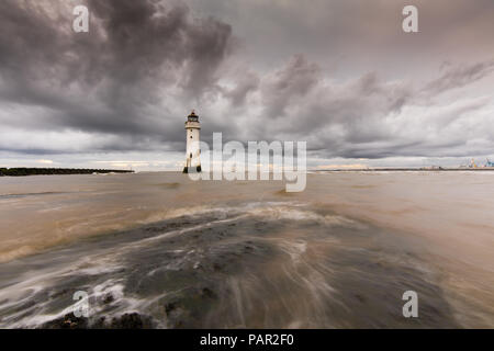 Stark bewölkt liegen über New Brighton Leuchtturm, mit Wasser wirbeln über die Felsen, die Tide hetzt über Sie. Stockfoto