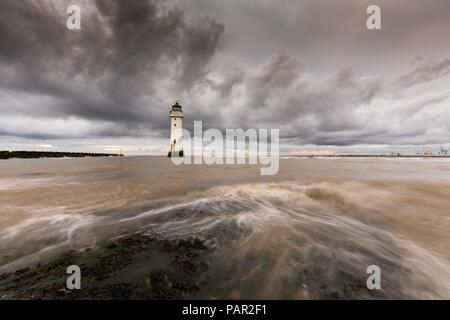 Stark bewölkt liegen über New Brighton Leuchtturm, mit Wasser wirbeln über die Felsen, die Tide hetzt über Sie. Stockfoto