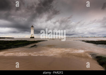 Stark bewölkt liegen über New Brighton Leuchtturm, mit Wasser wirbeln über die Felsen, die Tide hetzt über Sie. Stockfoto