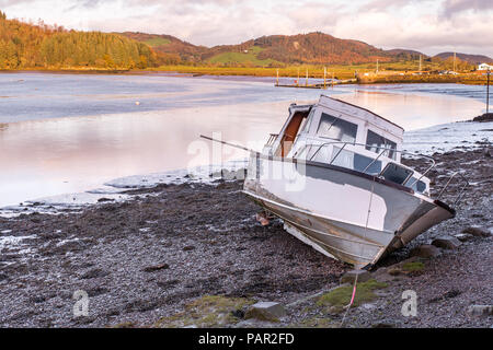Ein Motorboot liegt auf dem Schlamm warten auf die Flut Kippford, in der Nähe von Dalbeattie zurückzukehren, in Dumfries und Galloway, Schottland mit dem Segeln Stockfoto