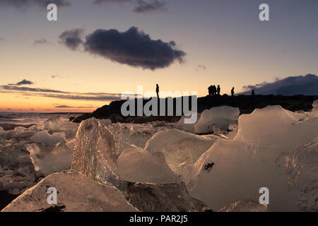 Ein Tourist steht gegen den Abendhimmel, als gerade die Sonne über Diamond Beach im Süden Islands set Silhouette Stockfoto