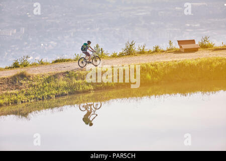 Österreich, Tirol, weibliche Mountainbiker am See im Abendlicht Stockfoto