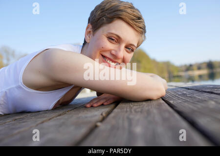 Portrait von Frau liegend auf Jetty Stockfoto