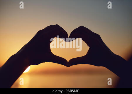 Herzen von Händen gemacht auf einen Sonnenuntergang. Stockfoto
