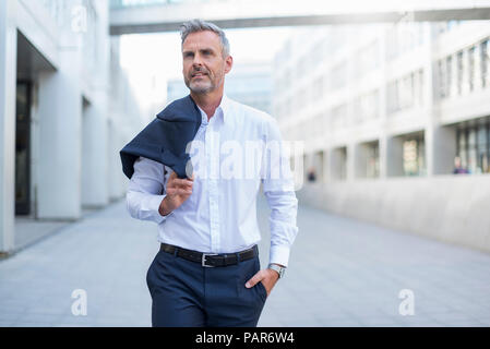 Portrait von Geschäftsmann walking im Innenhof der modernen Bürogebäude Stockfoto